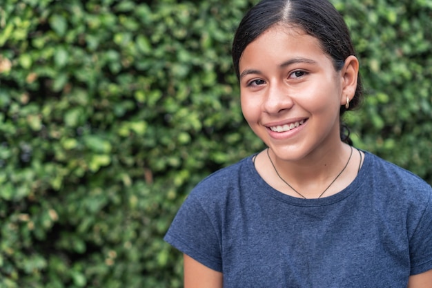 Teenager smiling in a park and looking at the camera.