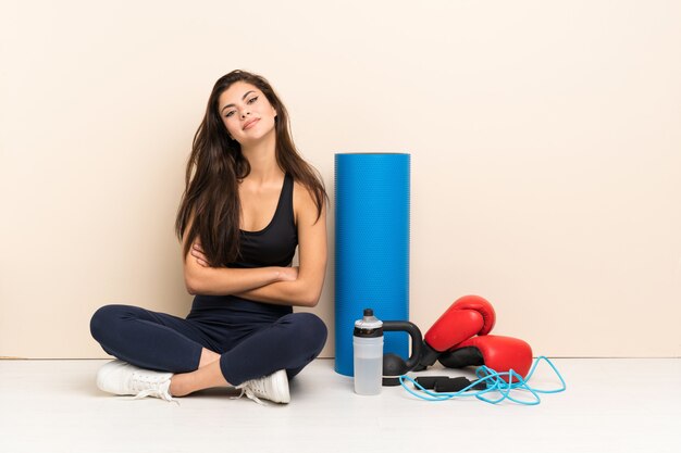 Teenager sport girl sitting on the floor keeping the arms crossed in frontal position