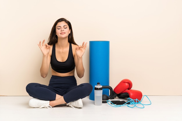 Teenager sport girl sitting on the floor in zen pose