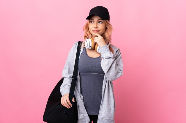 Teenager sport woman with sport bag over isolated background having doubts and thinking