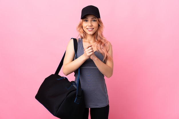 Teenager sport woman with sport bag over isolated  laughing