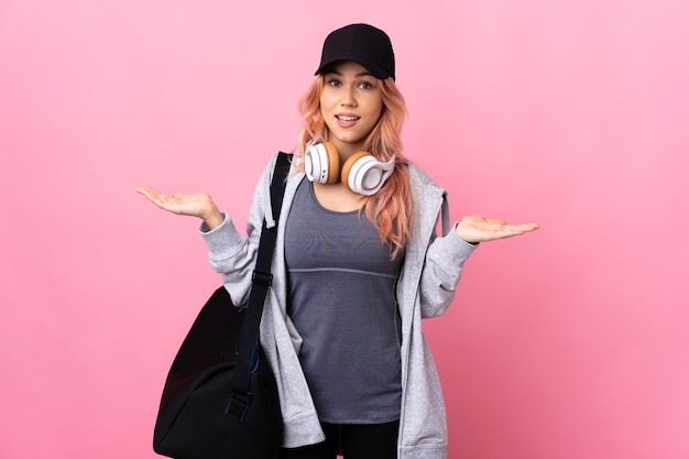 Photo teenager sport woman with sport bag over isolated wall with shocked facial expression