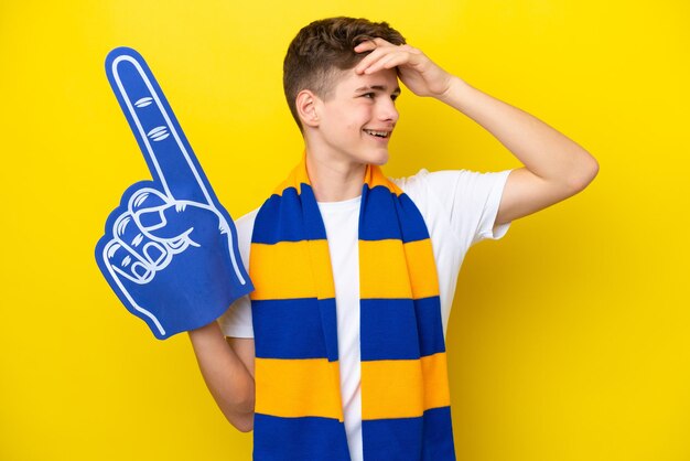 Teenager sports fan man isolated on yellow background smiling a lot