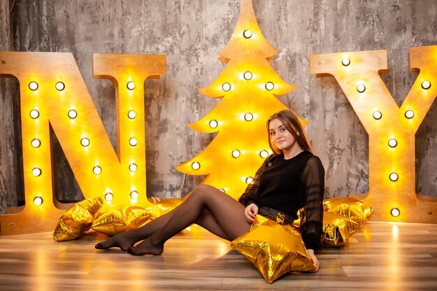 A teenager stands near a christmas tree with many toys new year\
holidays at school in europe