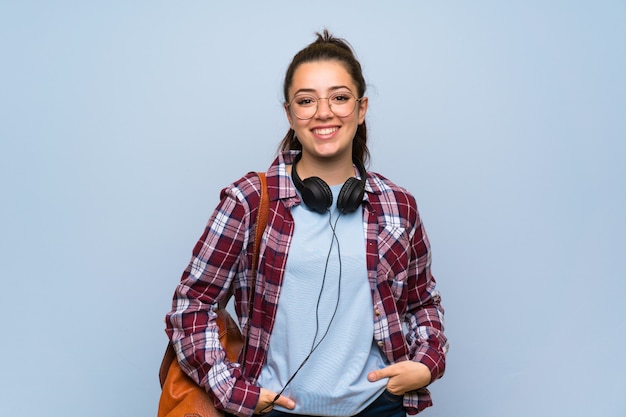 Teenager student girl over isolated blue wall laughing