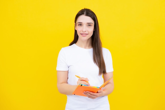 Teenager student girl isolated on yellow background Cheerful young woman student in shirt hold notebooks showing High school university college students