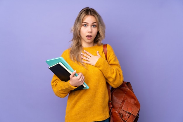 Teenager student girl on purple wall surprised and shocked while looking right
