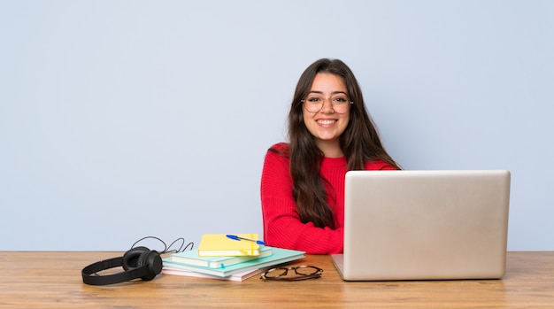 La ragazza dello studente dell'adolescente che studia in una tavola che tiene le armi ha attraversato nella posizione frontale