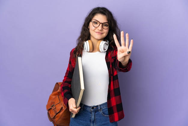 Teenager student isolated on purple wall happy and counting four with fingers