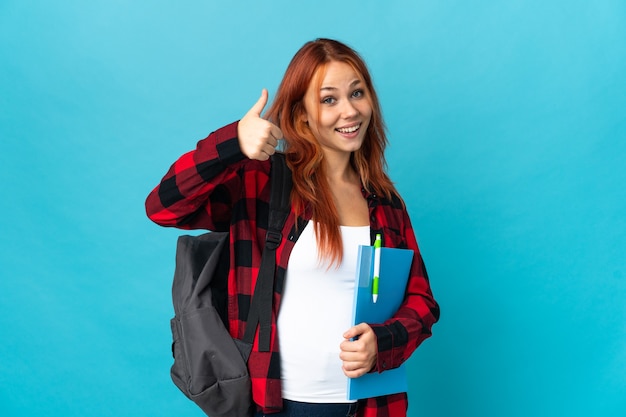 Teenager student Russian girl on blue giving a thumbs up gesture