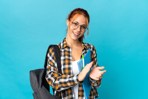 Teenager student Russian girl isolated on blue wall applauding