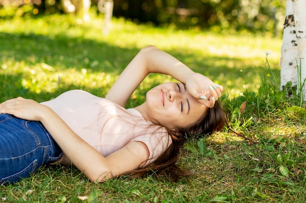 10 代の夏の幸せな学生は草の上に横たわって、牧草地で夏と晴れた天気を楽しんで笑っている