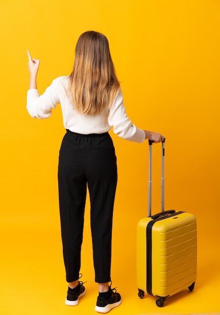 Teenager traveler girl over isolated yellow wall