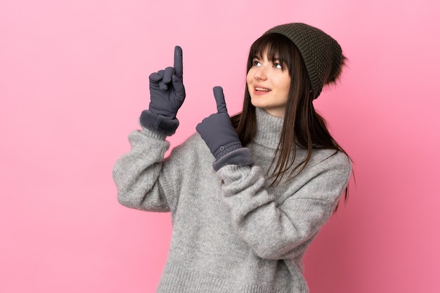 Teenager Ukrainian girl with winter hat isolated on white background pointing with the index finger a great idea