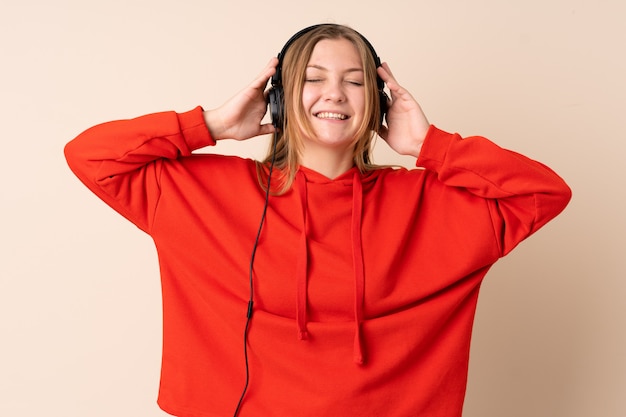 Teenager ukrainian woman isolated on beige space listening music