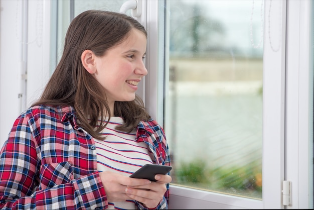 Teenager using phone near the window