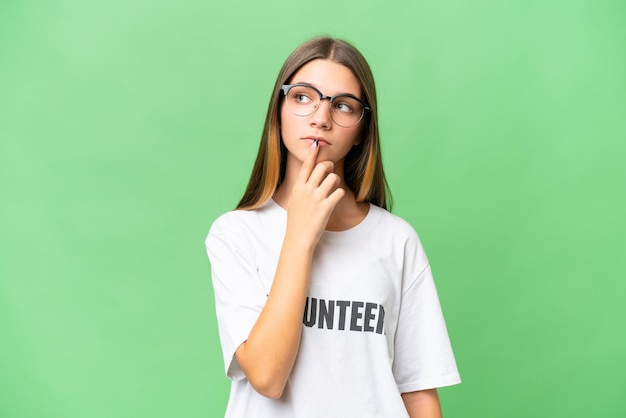 Teenager volunteer caucasian girl over isolated background having doubts while looking up