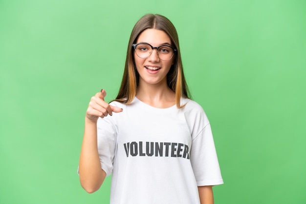 Teenager volunteer caucasian girl over isolated background surprised and pointing front