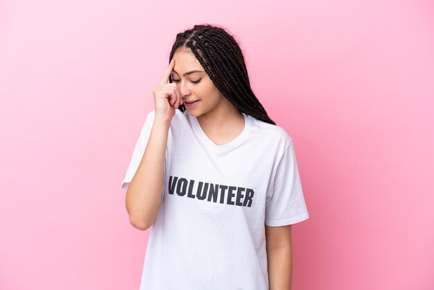 Teenager volunteer girl with braids isolated on pink background laughing