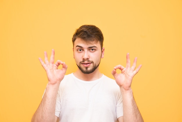 teenager with a beard on yellow  showing a gesture OK