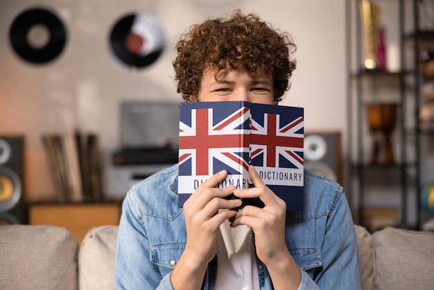 A teenager with curly hair sits focused in a room studying for an english exam