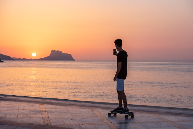Teenager with his long board in promenade