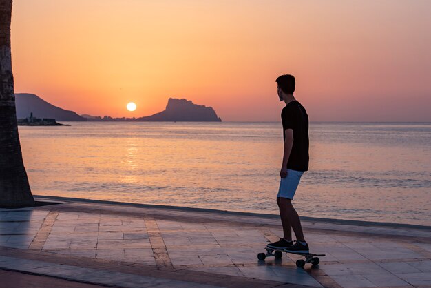 Teenager with his long board in promenade