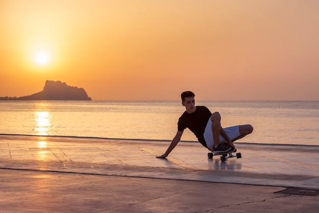 Teenager with his long board in promenade