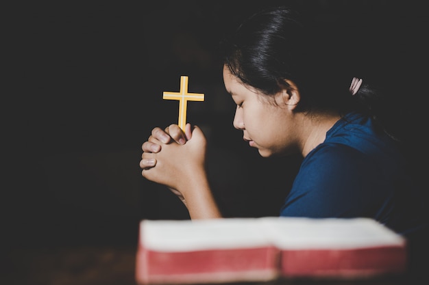 Teenager woman hand with Cross and Bible praying, Hands folded in prayer 