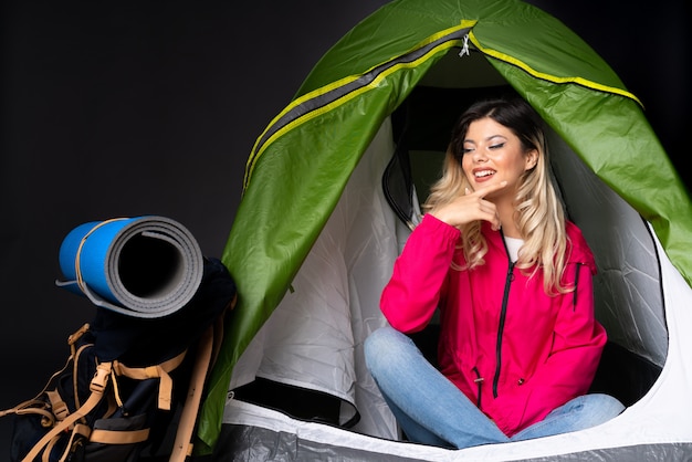 Фото Подросток женщина в палатке зеленый кемпинг, изолированные на черной стене, глядя в сторону