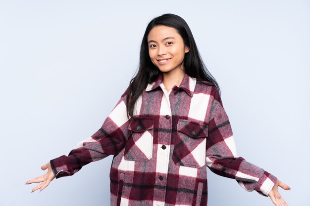 Teenager woman isolated on blue happy and smiling