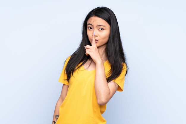 Teenager woman isolated on blue showing a sign of silence gesture putting finger in mouth