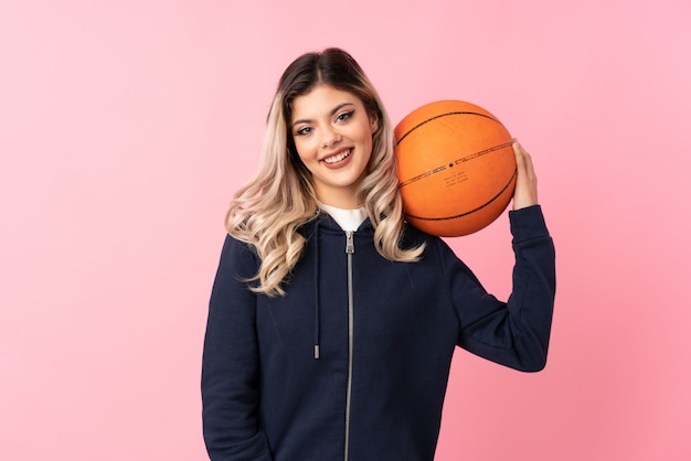 Donna dell'adolescente sopra il rosa isolato con la palla di pallacanestro