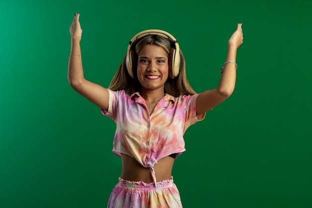 Photo teenager woman in studio photo with green background doing poses and facial expressions and with headphones