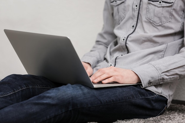 Teenager working with laptop while sitting on floor at home closeup