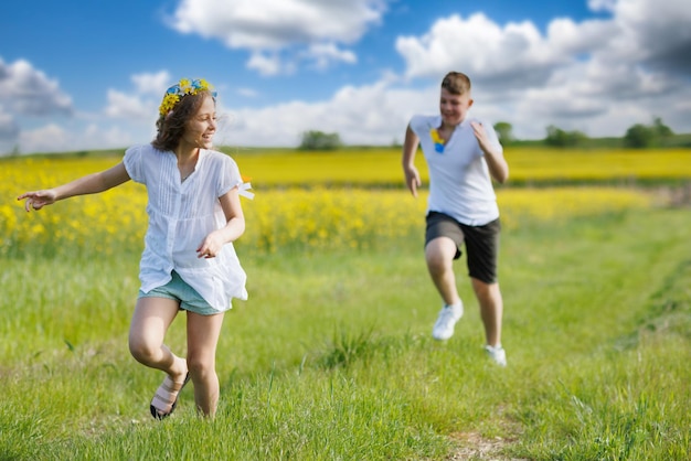 십대 형제와 자매는 흐린 하늘을 배경으로 초원에서 달리고 날씨를 즐기고 있습니다