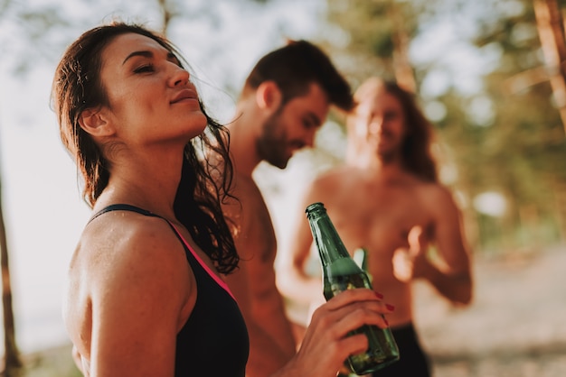 Azienda di adolescenti che beve birra sulla spiaggia.