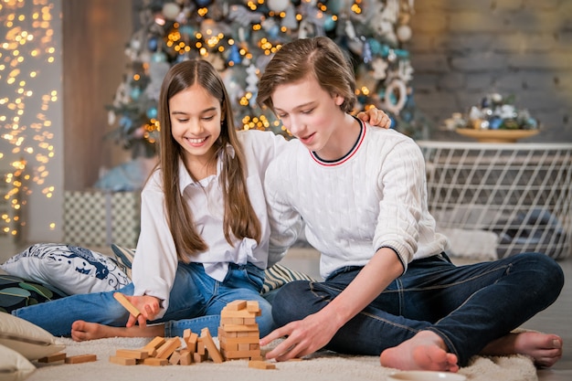 teenagers girl and boy playing board game in christmas interior at home