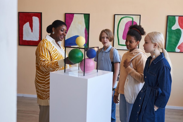Photo teenagers listening to teacher or tour guide in modern art gallery