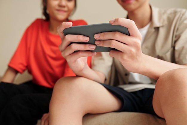 10 代の若者がスマートフォンでゲームをプレイ
