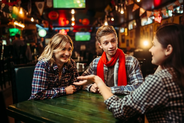 Teenagers sitting at the table in sports bar.