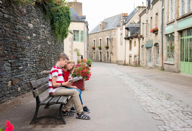 Teenagers travel sitting on the bench in the street of an old Europe town RochefortenTerre France