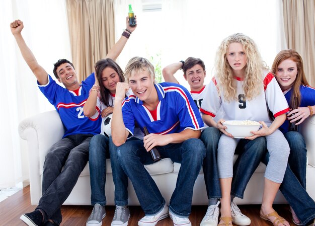 Teenagers watching a football match at home