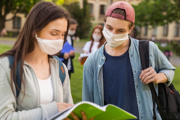 Photo teenagers with face masks discussing project