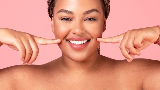 Teeth alignment and whitening concept Happy black body positive lady pointing at her wide smile closeup panorama