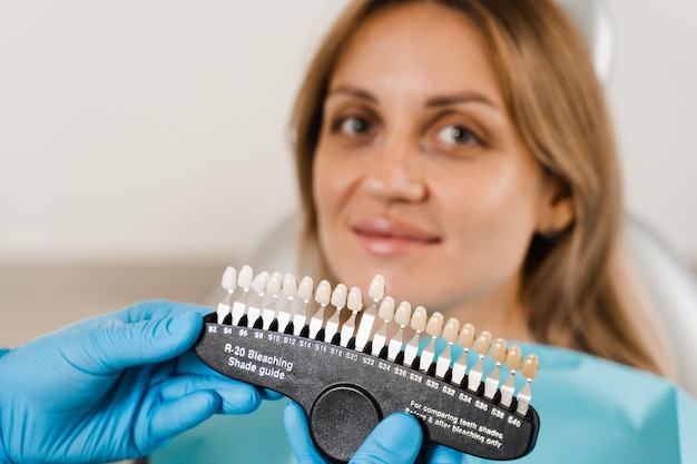 Foto guida alle sfumature di colore dei denti con paziente donna sbiancamento dei denti dentista che lavora con campioni di corrispondenza del colore dei denti nella clinica dentale odontoiatria