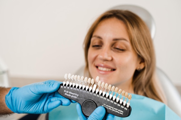 Фото Руководство по оттенкам цвета зубов с пациенткой-женщиной отбеливание зубов стоматолог, работающий с образцами цвета зубов в стоматологической клинике стоматология