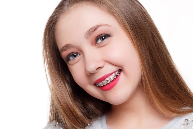 歯、感情、健康、人々、歯科医、ライフスタイルのコンセプト-健康で美しい笑顔、歯科医への子供。歯科矯正器具を持った少女の肖像。