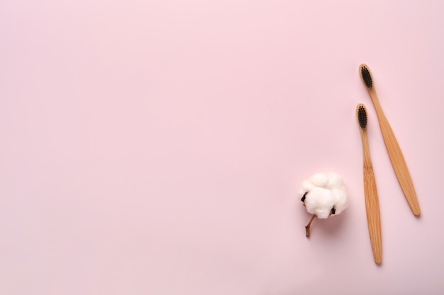 Teeth hygiene and oral dental care products on pink color
background with copy space. eco-friendly bamboo toothbrushes and
cotton flowers. flat lay, top view composition, mockup. morning
concept.