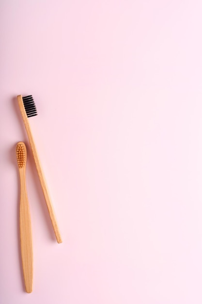 Teeth hygiene and oral dental care products on pink color\
background with copy space. eco-friendly bamboo toothbrushes and\
cotton flowers. flat lay, top view composition, mockup. morning\
concept.